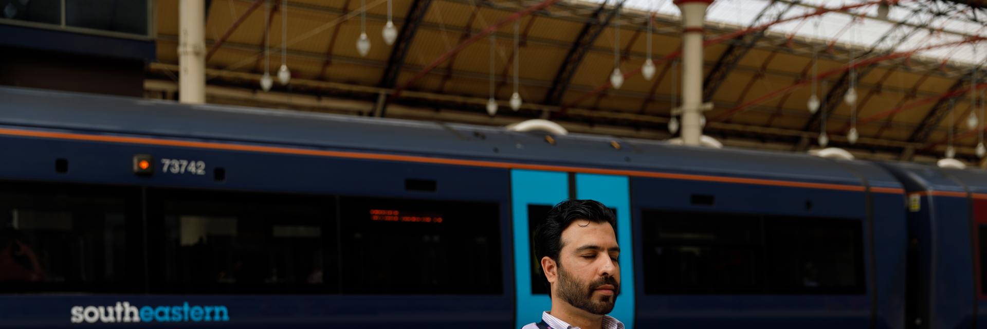 Rail worker sat on a seat at a station, meditating