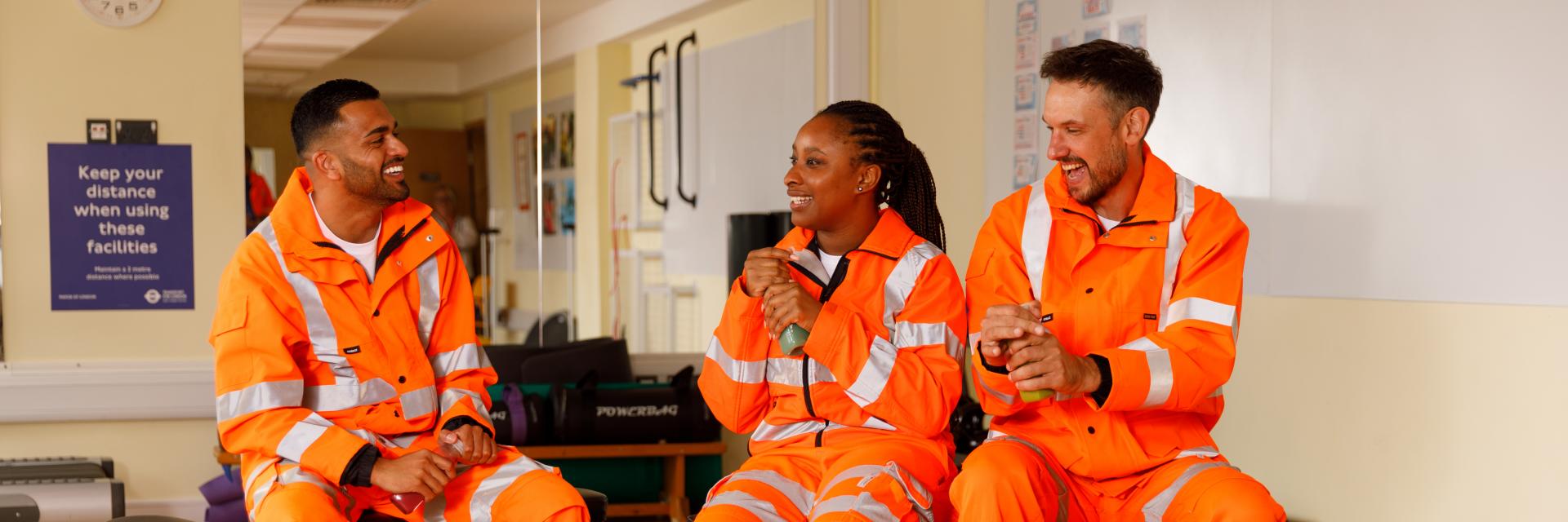 three rail workers sat down, smiling and talking